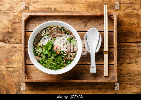 Pho Bo-vietnamesische Suppe mit Rindfleisch in Holztablett auf hölzernen Hintergrund Stockfoto