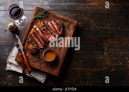 Gegrillte Scheiben Steak-Rib-Eye mit Pfeffersauce und Rotwein auf hölzernen Hintergrund Textfreiraum Stockfoto