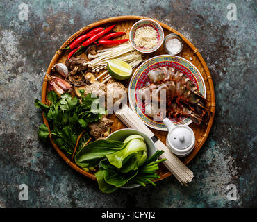 Zutaten für asiatische Kochen mit Tiger Garnelen, Udon-Nudeln, Champignons, grünen Gemüse, Gewürze auf Bambus Tablett auf Metall Hintergrund Stockfoto