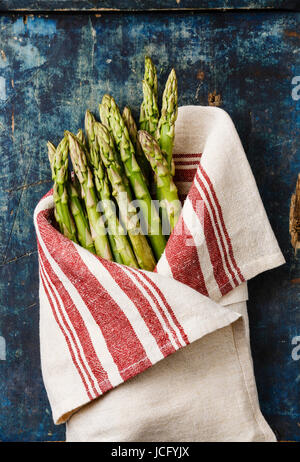 Frisches rohes Grünspargel Handtuch auf blauem Hintergrund aus Holz Stockfoto