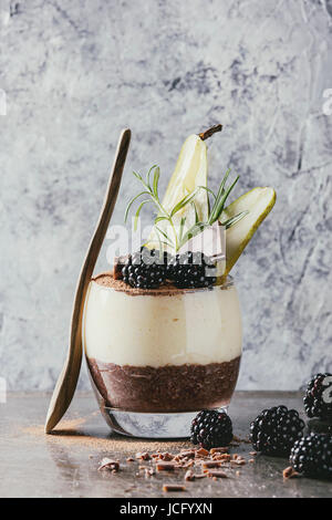 Dessert Frühstück geschichteten Chia-Samen, Schoko-Pudding, Reis Brei aus Glas dekoriert mit frischen Brombeeren, in Scheiben geschnitten Birne, Kakaopulver. Stehen mit Stockfoto