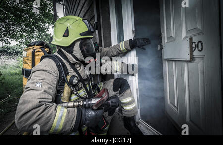 Feuerwehr mit Atemschutz und einen Schlauch in einem verrauchten Raum in einem inländischen Haus. Stockfoto