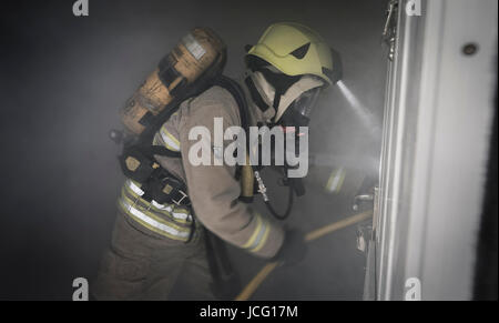 Feuerwehr mit Atemschutz und einen Schlauch in einem verrauchten Raum in einem inländischen Haus. Stockfoto