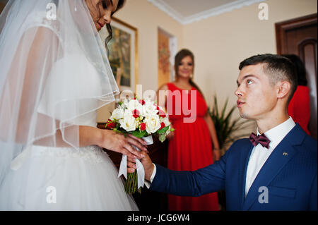 Bräutigam kniet küßt Hand einer Braut und gibt ihr einen schönen Strauß Rosen. Stockfoto