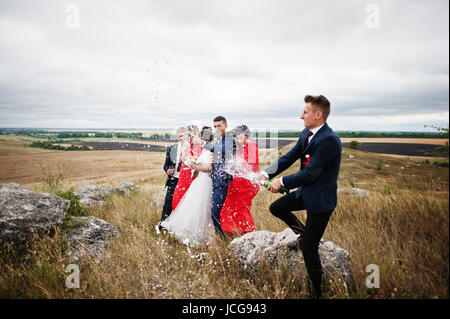 Brautführer oder Trauzeuge, die Öffnung der Flasche Champagner auf dem Lande mit Hochzeitspaar und Braidsmaids mit Brautführer stehend in die Hinterg Stockfoto