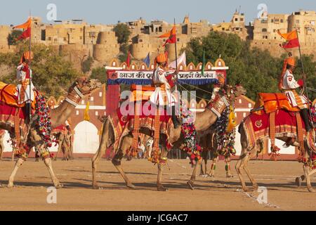 Kamele und Fahrer der Border Security Force ausführen vor Jaisalmer Fort in der Wüste Festival in Jaisalmer, Rajasthan, Indien. Stockfoto