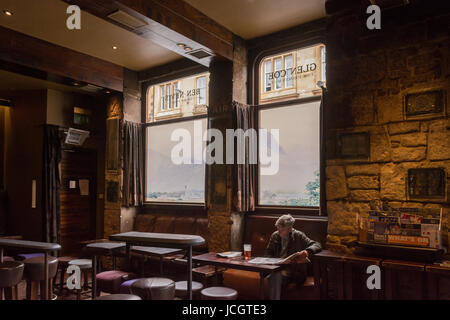 Der Ben Nevis Pub, Finnieston, Glasgow, Schottland - Mann trinkt Bier und Zeitunglesen vor Ben Nevis Szene gemalt auf windows Stockfoto