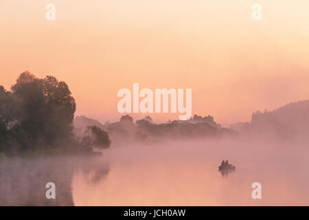 Zwei Angler auf einem Boot genießt Angeln an einem schönen Morgen. Ein nebliger Morgen auf dem See. Angelboot/Fischerboot an einem nebligen Fluß. Platz für Text. Stockfoto