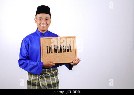 Junger Mann lächelnd mit Tafel für Eid Fitr oder Eid Adha feiern. Stockfoto