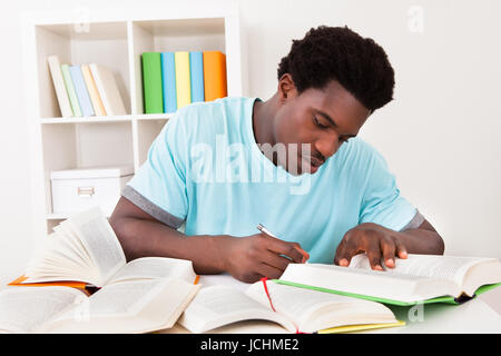 Junge Afrikaner Studium zu Hause mit eine Menge Bücher Stockfoto