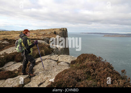 Eine Hügel-Walker blickt auf das Meer vom Klippe Weg zu Fair Head, Ballycastle, County Antrim, Nordirland. Stockfoto