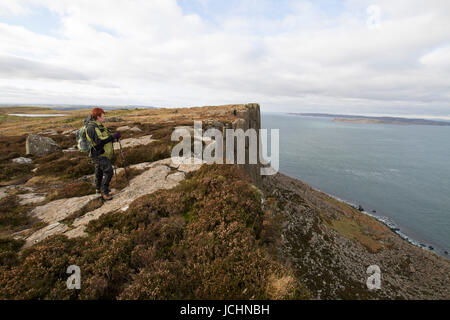 Eine Hügel-Walker blickt auf das Meer vom Klippe Weg zu Fair Head, Ballycastle, County Antrim, Nordirland. Stockfoto