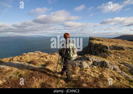 Eine Hügel-Walker blickt auf das Meer vom Klippe Weg zu Fair Head, Ballycastle, County Antrim, Nordirland. Stockfoto