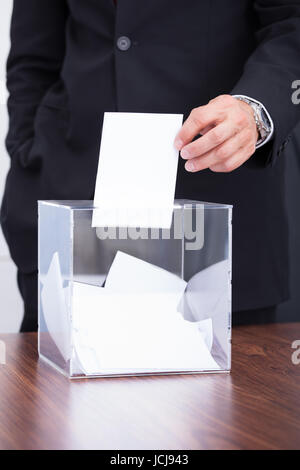 Glücklich reifer Geschäftsmann Stimmzettel In transparenter Box einfügen Stockfoto