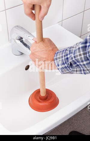Porträt von männlichen Klempner mit Kolben im Waschbecken im Bad Stockfoto