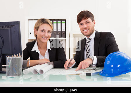Draufsicht eines männlichen und weiblichen Architekten diskutieren eine Reihe von Plänen, die auf einem Tisch ausgebreitet beschnitten Stockfoto