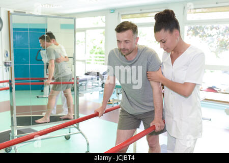 Mann auf Laufband mit Therapeuten hocken im Fitness-studio Stockfoto