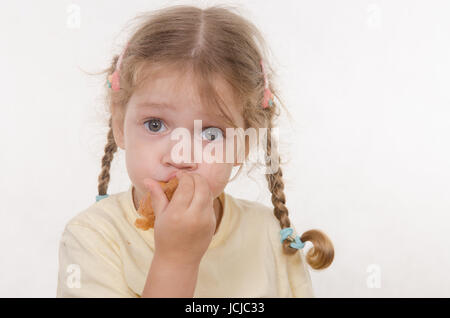 Drei Jahre altes Mädchen mit Zöpfen und lustig mit Begeisterung eine Brötchen essen Stockfoto