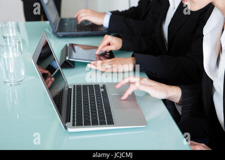 View-Bild aus einer Reihe von Geschäftsleuten auf Laptops und Tablets beschnitten während einer Präsentation oder Tagung Stockfoto