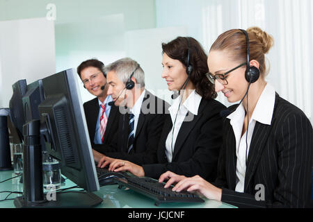 Linie von professionellen stilvolle Call-Center-Betreiber tragen Kopfhörer sitzt hinter ihren Computern Hilfeleistung Stockfoto