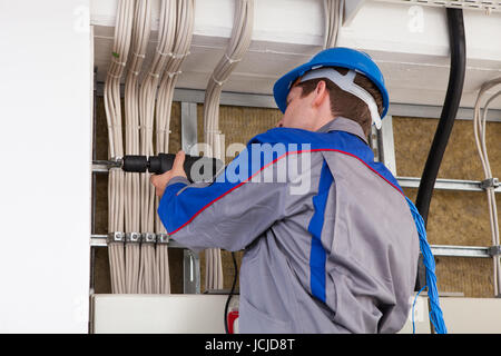 Männliche Arbeiter mit Bohrmaschine arbeiten im Büro Stockfoto