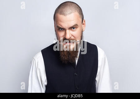 Wütend. Gut aussehend Geschäftsmann mit Bart und Schnurrbart Blick in die Kamera mit wütendes Gesicht. Studio gedreht, auf grauem Hintergrund. Stockfoto