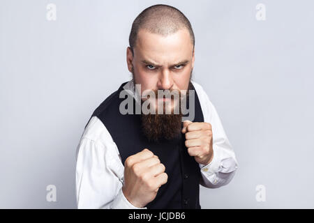 Wütend Boxen. Gut aussehend Geschäftsmann mit Bart und Schnurrbart Blick in die Kamera mit wütendes Gesicht und Faust. Studio gedreht, auf grauem Hintergrund. Stockfoto