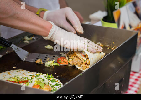 Nahaufnahme der Hände von Cook in Handschuhen Vorbereitung Fajitas oder Fajitos. Gesunde frische Tortillas mit gegrilltem Hähnchen Filet, Avocado, frische Salsa. Konzept der mexikanischen Küche. Party Essen. Stockfoto