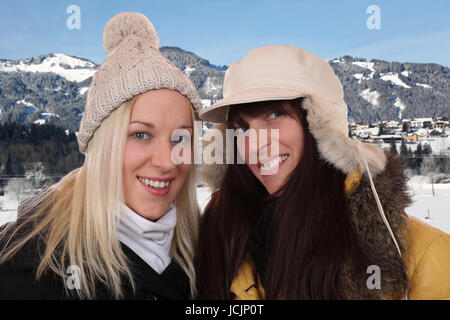 Zwei Lachende Frauen Mit Mütze Und Schal Machen Urlaub in Den Bergen Im Winter Stockfoto