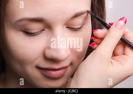 Make-up-Künstler malt der Augenbrauen eines schönen jungen Mädchens in der Verfassung Stockfoto