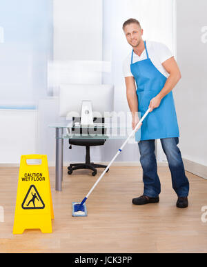 Gelben Warnhinweis, Menschen zu rutschig nassem Untergrund Vorsicht wie ein Hausmeister den Boden in einem Bürogebäude mops Stockfoto