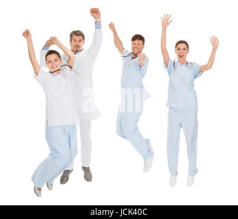 Gruppe von Ärzten mit dem Ausdruck ihrer Freude mit einer Steigerung der Hand Over White Background Stockfoto