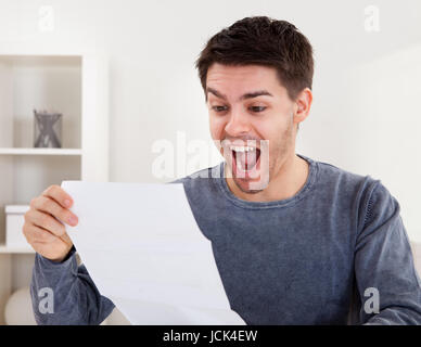 Jubelnder junger Mann Jubel bei gute Nachricht, die er nur in einem Dokument erhalten hat, die er liest Stockfoto