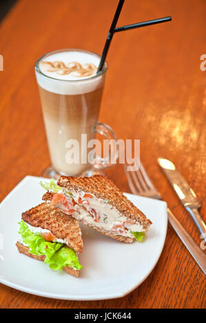 Sandwich mit Käse und Lachs und Gemüse mit latte Stockfoto