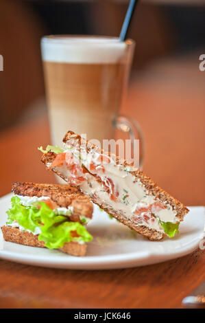 Sandwich mit Käse und Lachs und Gemüse mit latte Stockfoto