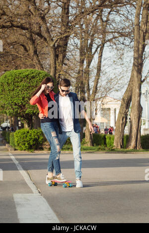 Verliebte Teenager. Der Kerl unterrichtet seine Freundin Skateboard. Datum der Hipster. Stockfoto