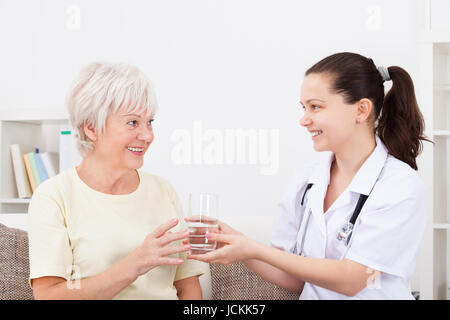 Glücklich Arzt Angebot Glas Wasser um zu Reifen, Patient Stockfoto