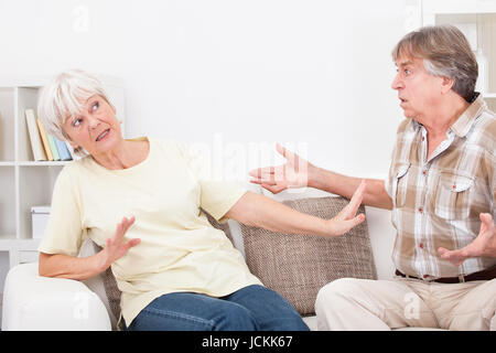 Portrait Of Senior Couple zu Hause auf der Couch sitzen streiten mit einander Stockfoto