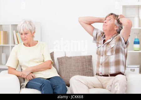 Portrait Of Senior Couple zu Hause auf der Couch sitzen streiten mit einander Stockfoto