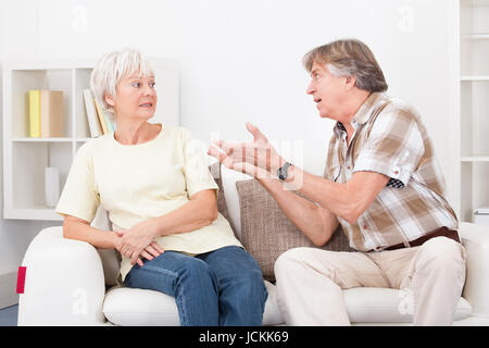 Portrait Of Senior Couple zu Hause auf der Couch sitzen streiten mit einander Stockfoto