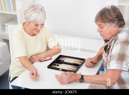 Gerne älteres paar Spiel von Backgammon zu Hause Stockfoto
