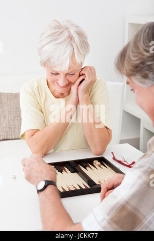 Gerne älteres paar Spiel von Backgammon zu Hause Stockfoto