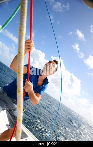 Junger Mann heben das Segel Katamaran während der Kreuzfahrt Stockfoto