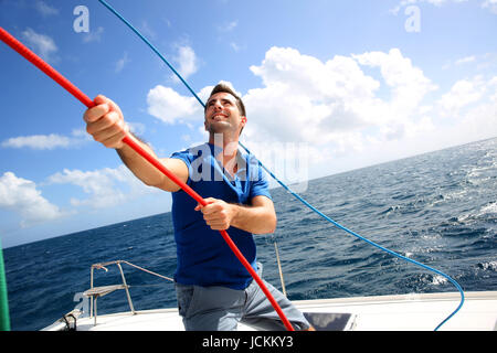 Junger Mann heben das Segel Katamaran während der Kreuzfahrt Stockfoto