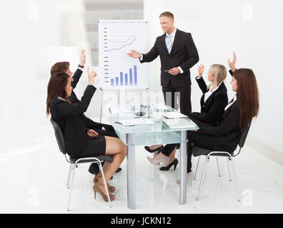 Geschäftsleute mit Händen angehoben Beantwortung Geschäftsmann in Meeting im Büro Stockfoto