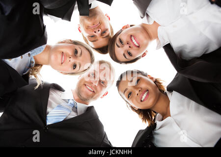 Niedrigen Winkel Porträt von Geschäftsleuten bilden Huddle vor weißem Hintergrund Stockfoto