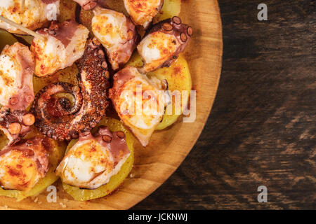 Eine Nahaufnahme Foto von Pulpo a la Gallega, ein Tintenfisch mit Salzkartoffeln, typische spanische galizische Gericht, auf einer traditionellen hölzernen Platte, mit Textfreiraum Stockfoto