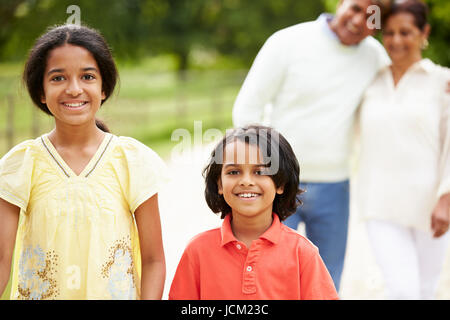 Indische Großeltern und Enkelkinder, die zu Fuß In Landschaft Stockfoto