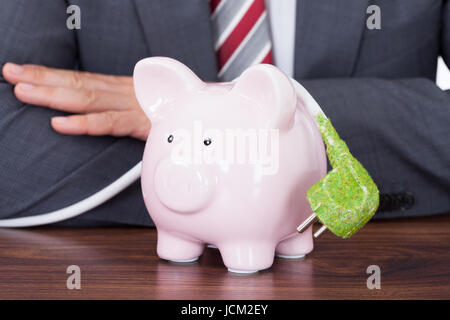 Mittelteil des Kaufmanns Abschirmung Sparschwein und grün Netzkabel am Schreibtisch Stockfoto