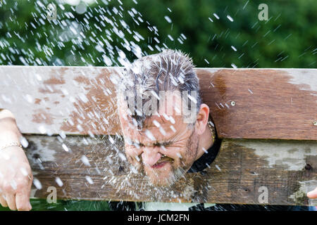 England, Coxheath. Welt Custard pie Meisterschaften. Mann in Stocks, erhalten durch die nassen Schwamm. Verschwommene Bewegung. Stockfoto